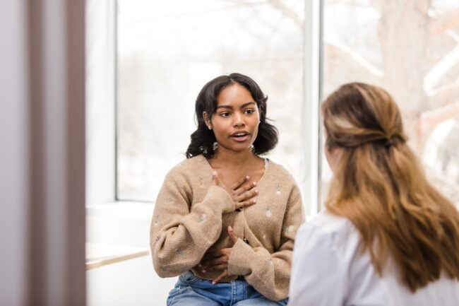 University student motions towards her chest as she describes the discomfort she has been experiencing