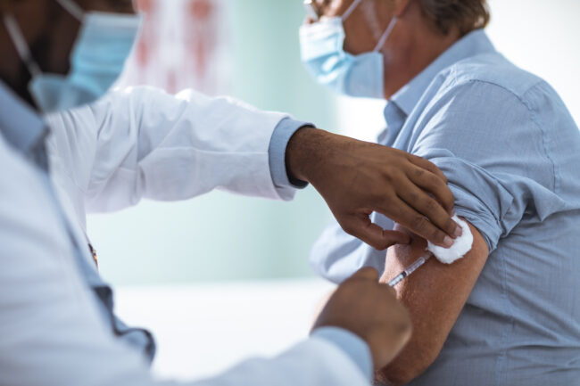 Mature man taking a vaccine from his doctor