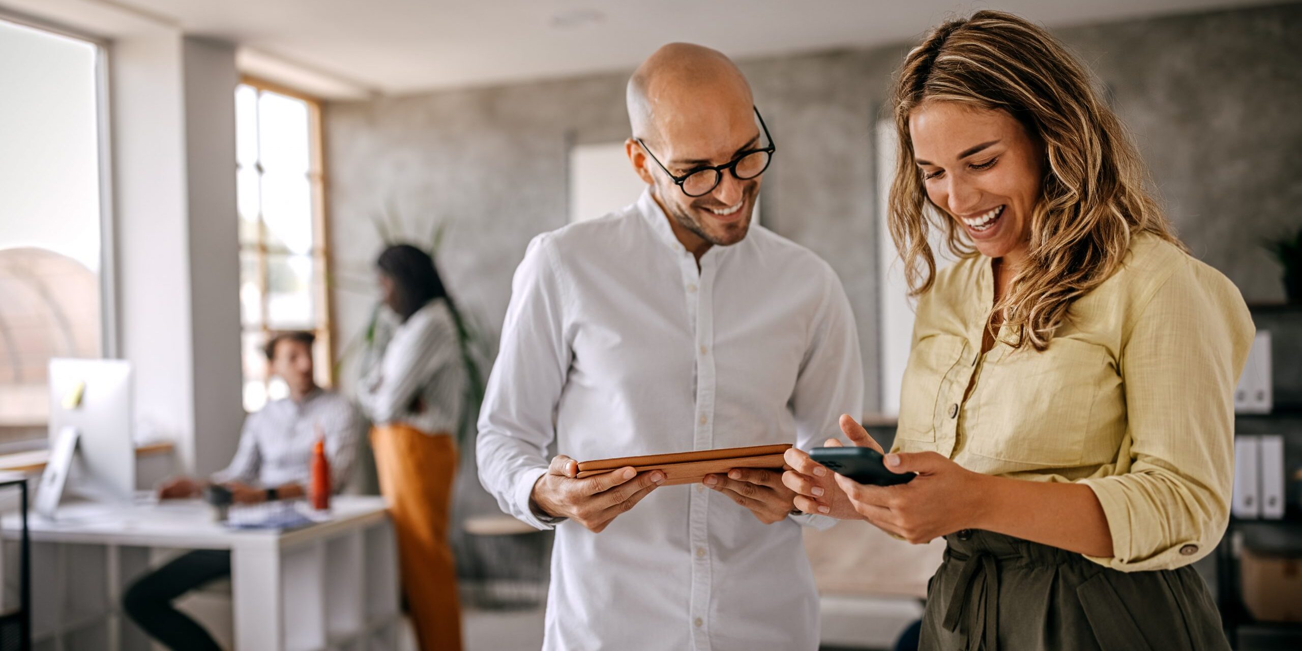 Businessman and businesswoman smiling looking at phone