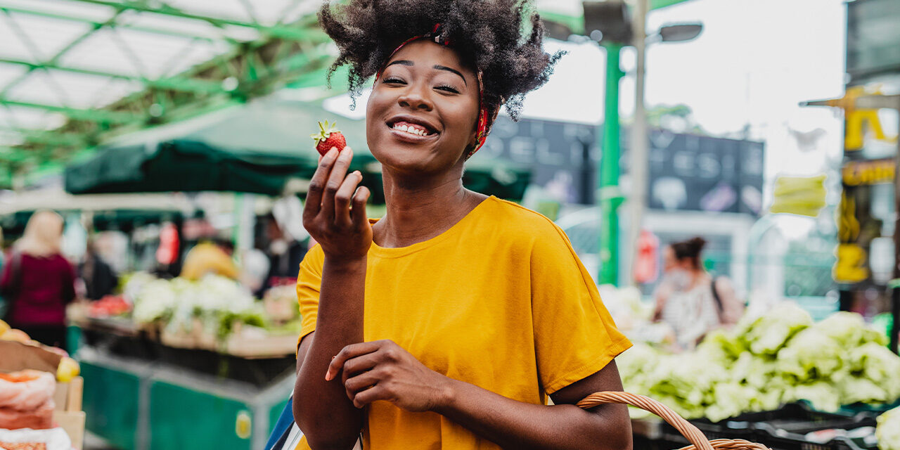 WomanEatingStrawberryAtFarmersMarket Woman enjoying a strawberry at the farmers market.