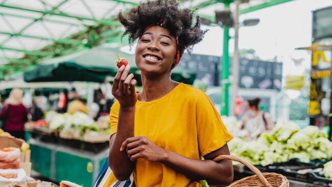 Woman enjoying a strawberry at the farmers market.