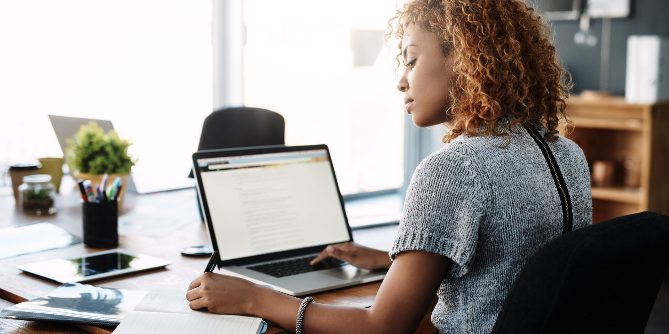 Young businesswoman taking notes on changing compliance regulations. Shot of a young businesswoman working on a laptop in an office