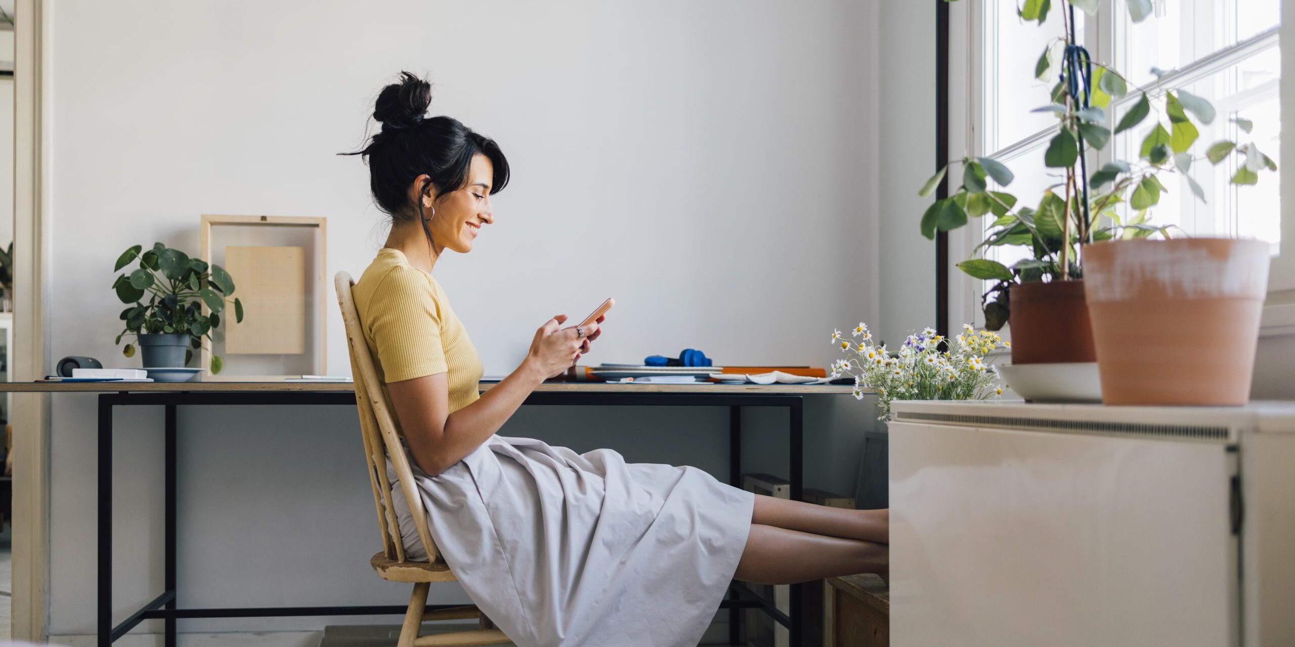 A Smiling Caucasian Female Businesswoman Texting On Her Mobile Phone While Sitting At Home