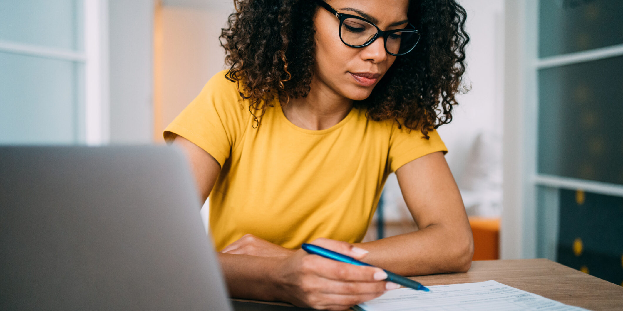 Businesswoman working in the office. Shot of an adorable african-american businesswoman using laptop and making notes on a clipboard inside of the office.