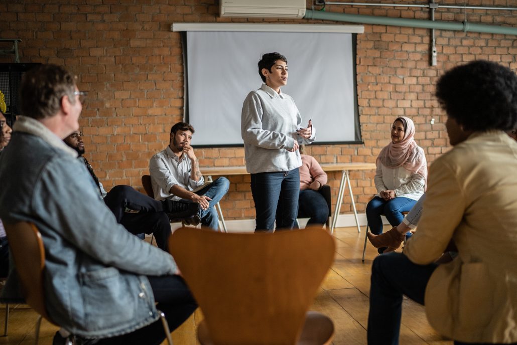 Young woman giving a lecture in an university or group therapy