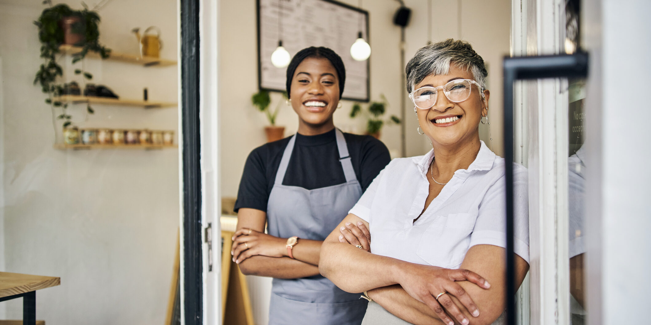 Coffee shop, senior woman manager portrait with barista feeling happy about shop success. Female server, waitress and small business owner together proud of cafe and bakery growth with a smile