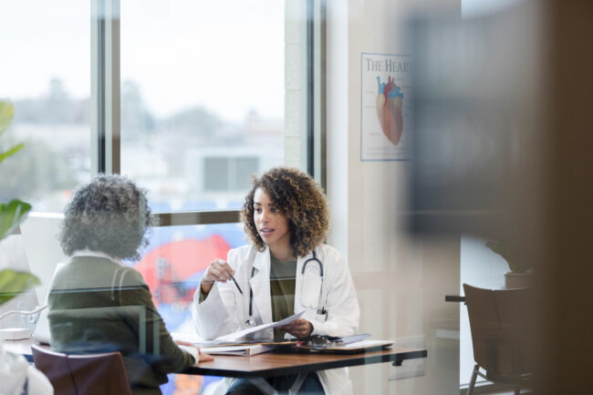 Female doctor and unrecognizable mature patient discuss treatment