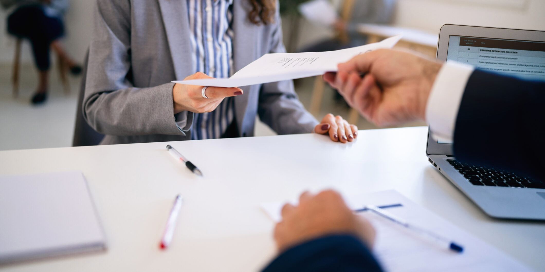 Female candidate, handing to a recruiter her resume during job interview In the office young Caucasian female candidate, giving her CV or application form to male recruiter during a job interview
