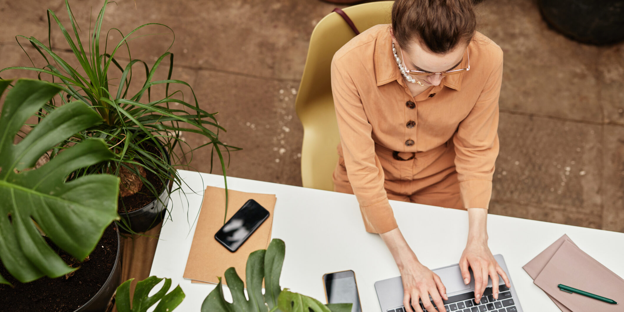 Above angle of young confident businesswoman typing on laptop keyboard