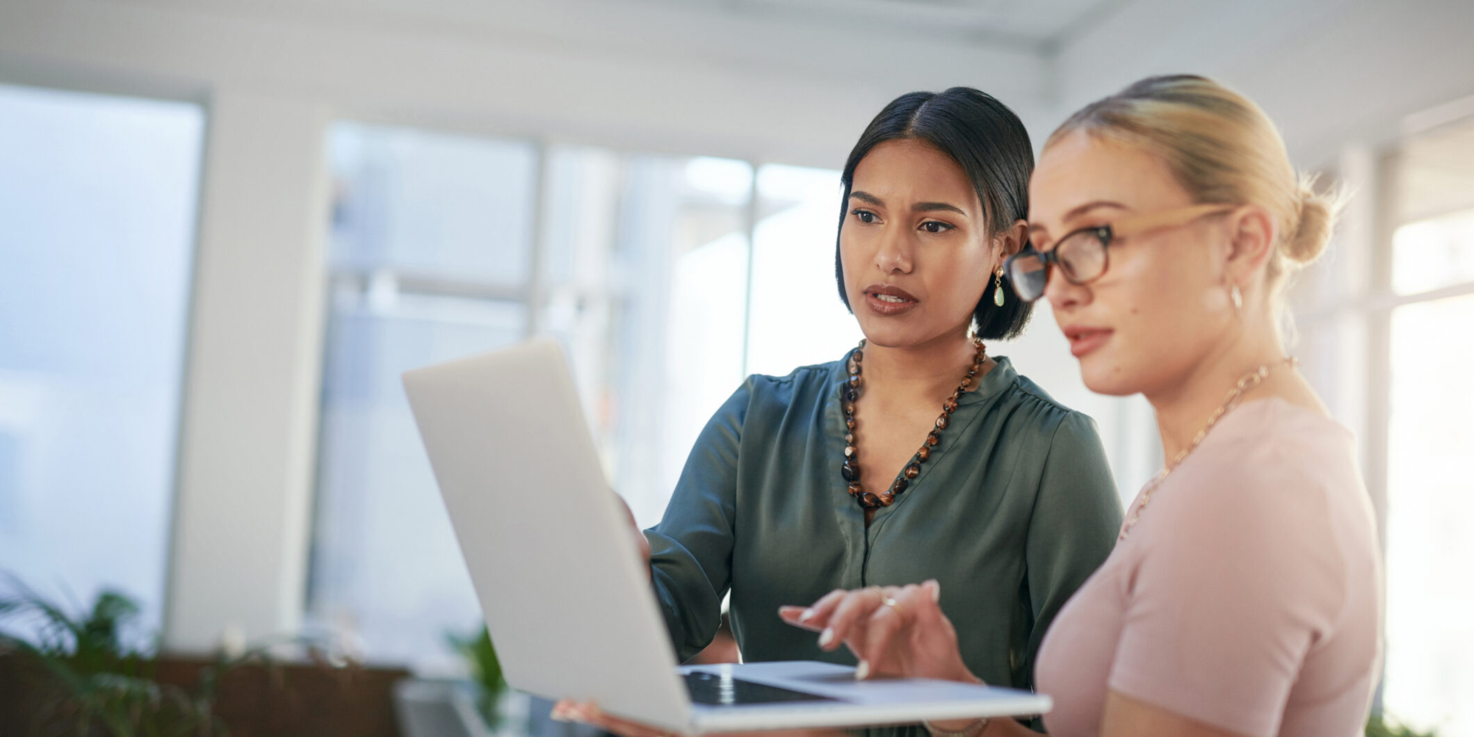 Shot of two young businesswomen using a laptop during a meeting in a modern office