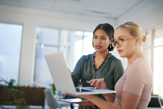 Shot of two young businesswomen using a laptop during a meeting in a modern office