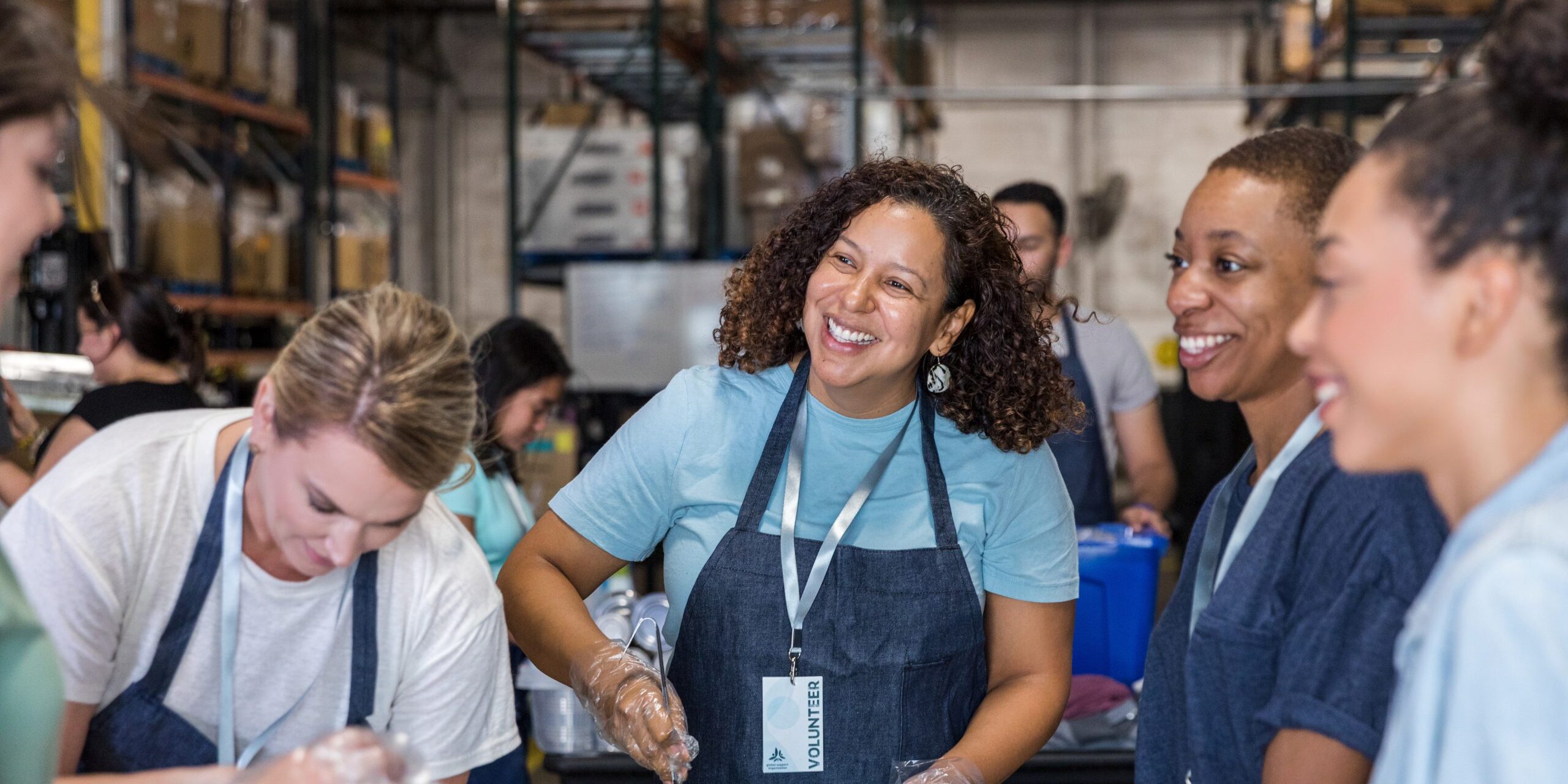 Women smile and talk while preparing food for soup kitchen