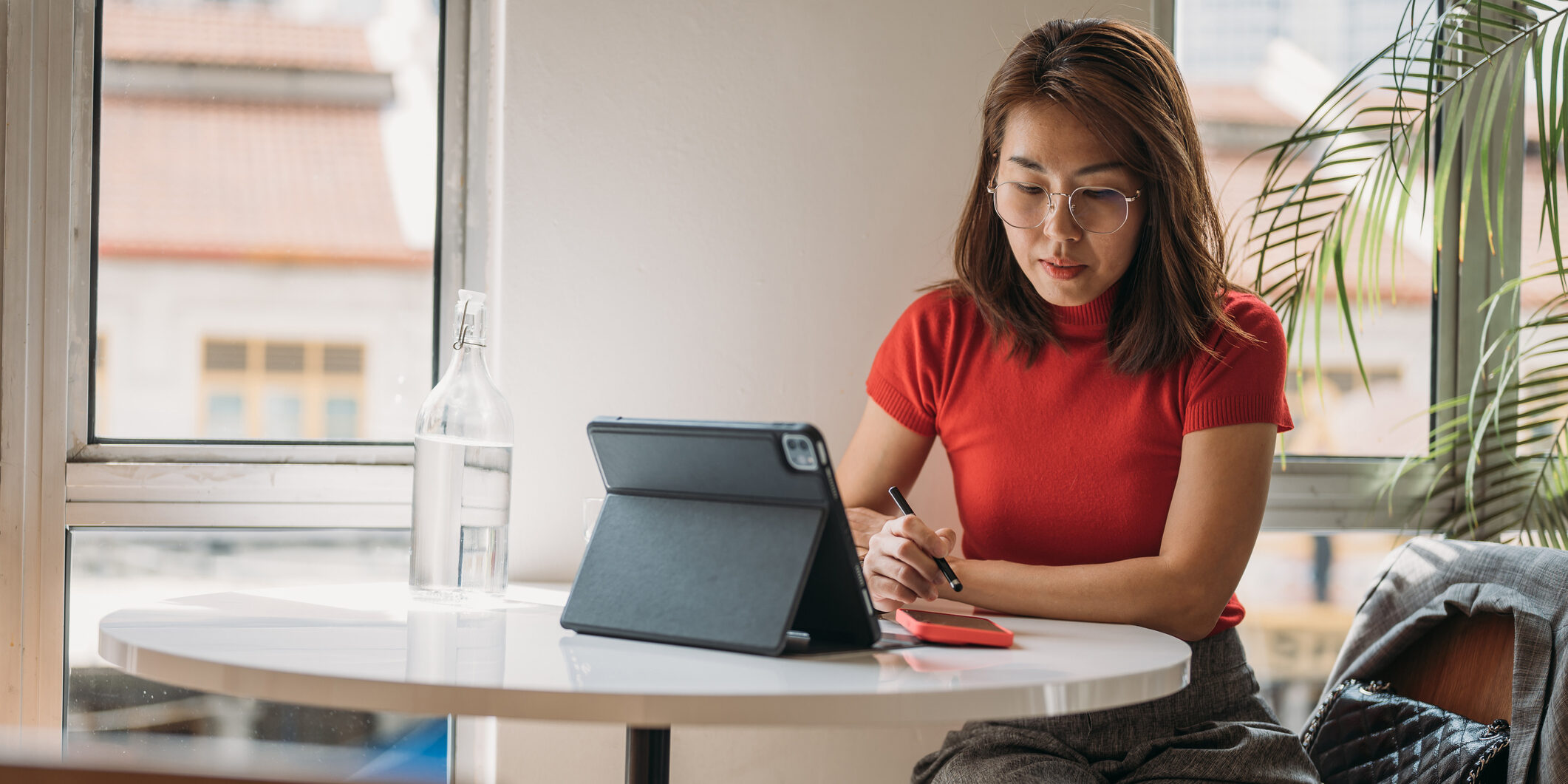 Woman working on digital tablet at Co Working Space . Businesswoman using tablet computer and smartphone.