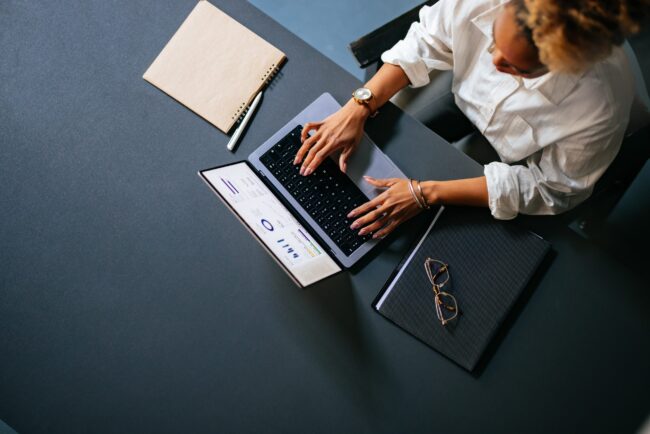 High Angle View Of Unrecognizable Woman Typing Business Report On A Laptop Keyboard In The Cafe