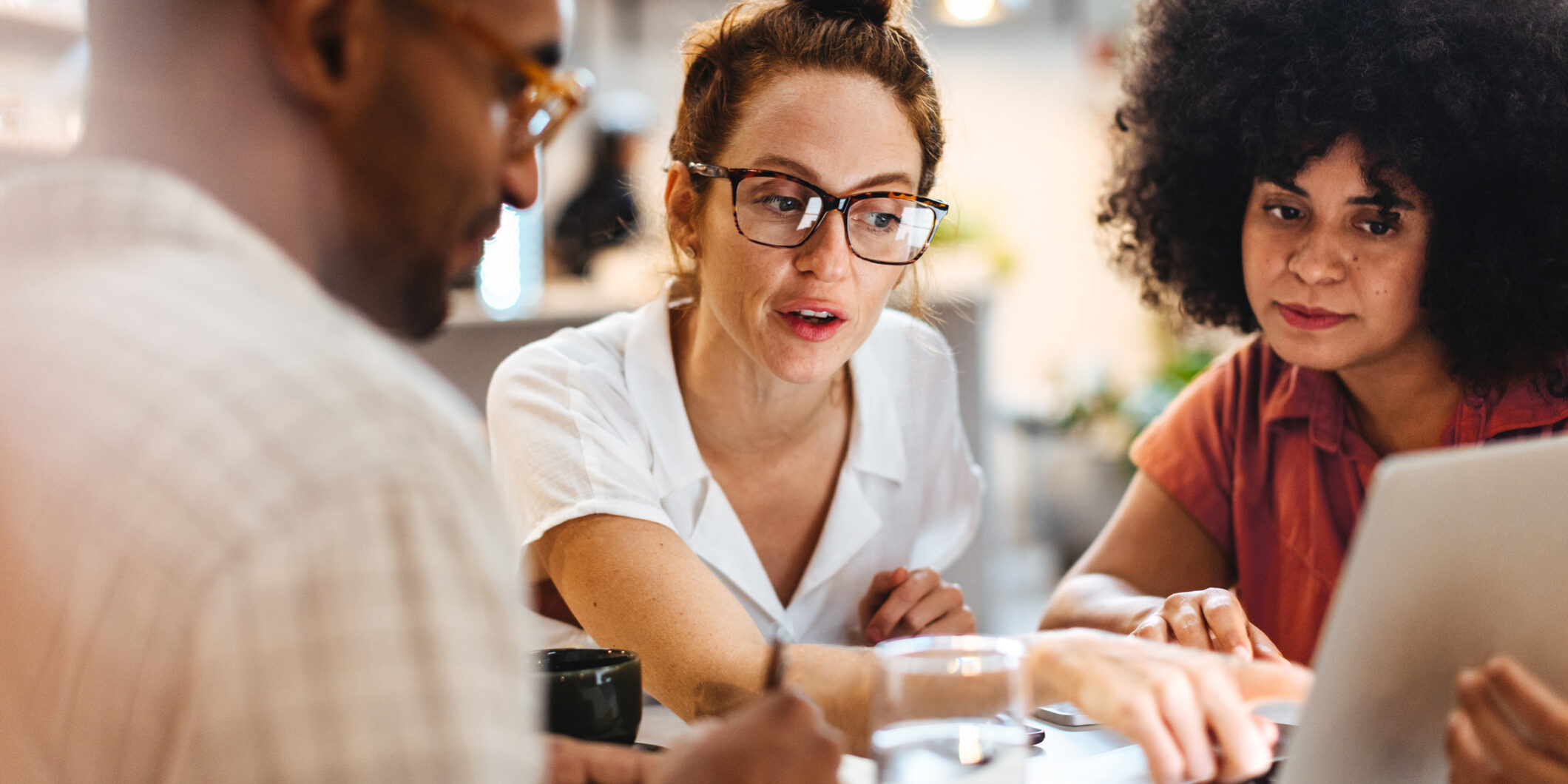 Business women having a discussion with a client over a business lunch Business women having a work lunch in a café, exchanging ideas and discussing their projects with a client. Young business team using a laptop as they sit around a coffee table.