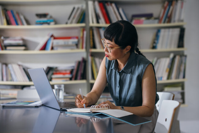 A Beautiful Asian Businesswoman With Glasses Using Her Computer While Working In The Office