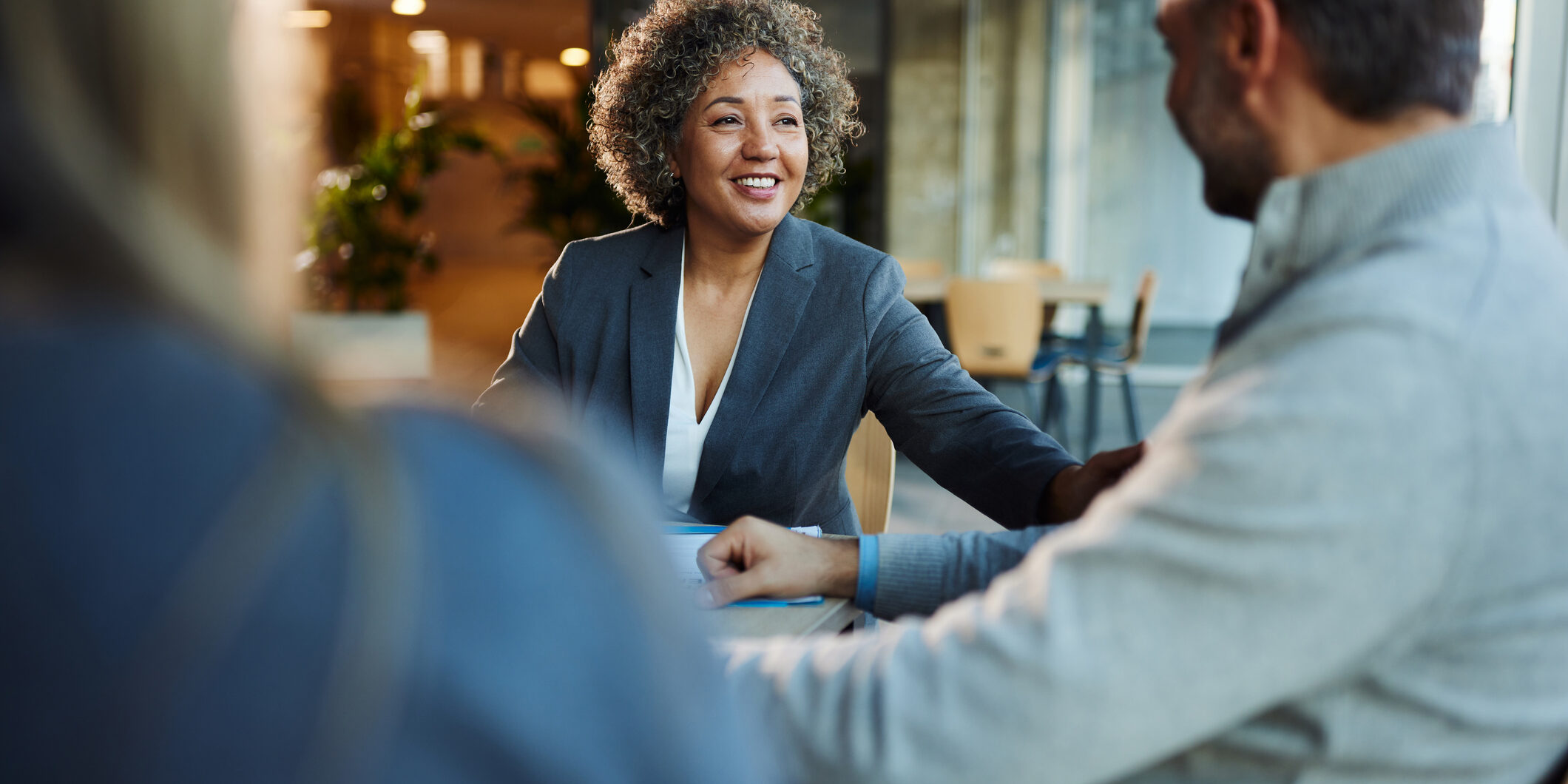 Happy insurance agent talking to her customers in the office.