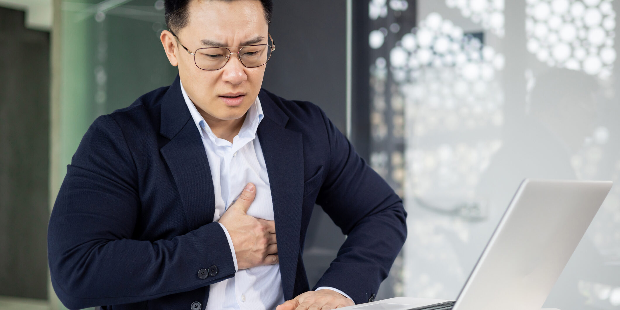 Businessman experiencing chest pain while working on laptop