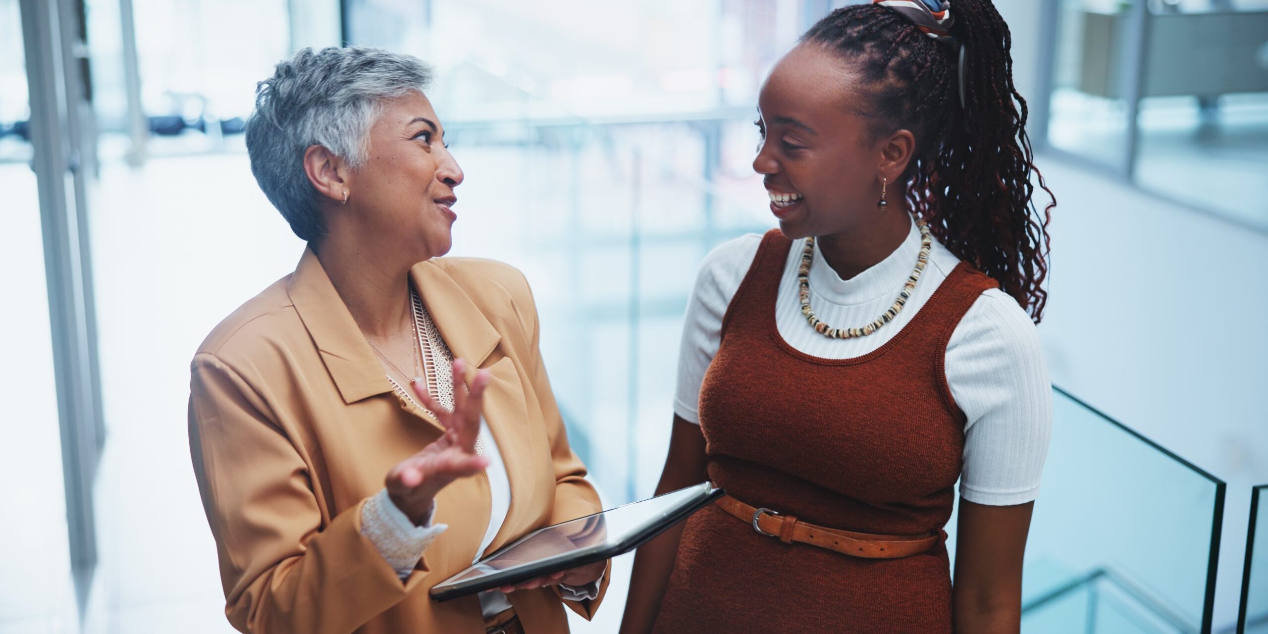 Businesspeople, tablet and consult with smile in office for advice with manager for executive assistance. Women, happy and tech for communication with support in workplace for coaching or help.