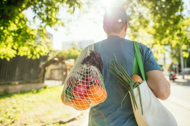 Senior man carrying fruits and vegetables in reusable shopping bag and mesh bag, environment conservation and sustainability concept