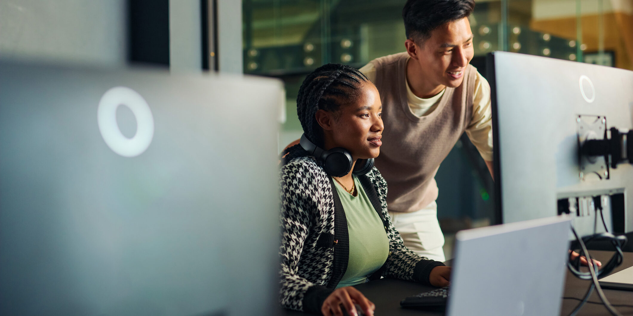 Software engineers collaborating on a project, analyzing code on computer monitors in office