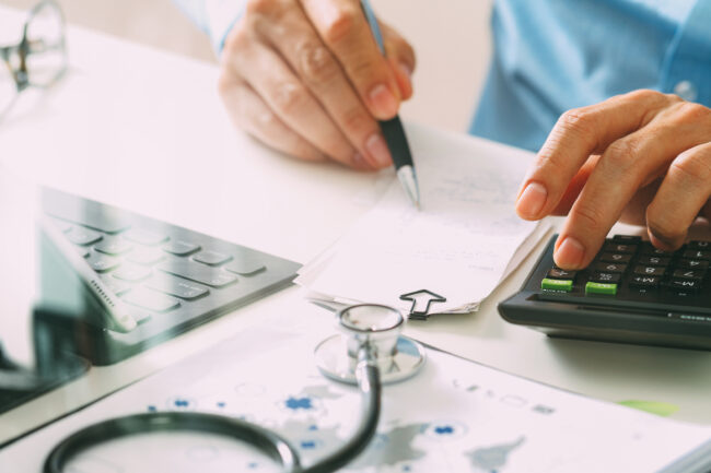Healthcare costs and fees concept.Hand of smart doctor used a calculator for medical costs in modern hospital